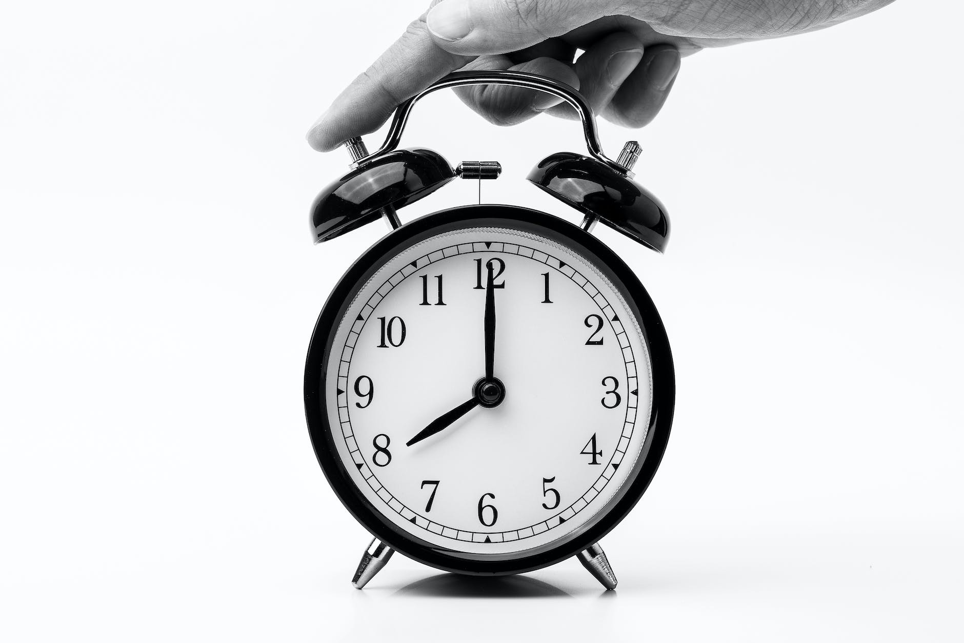 person touching black two bell alarm clock