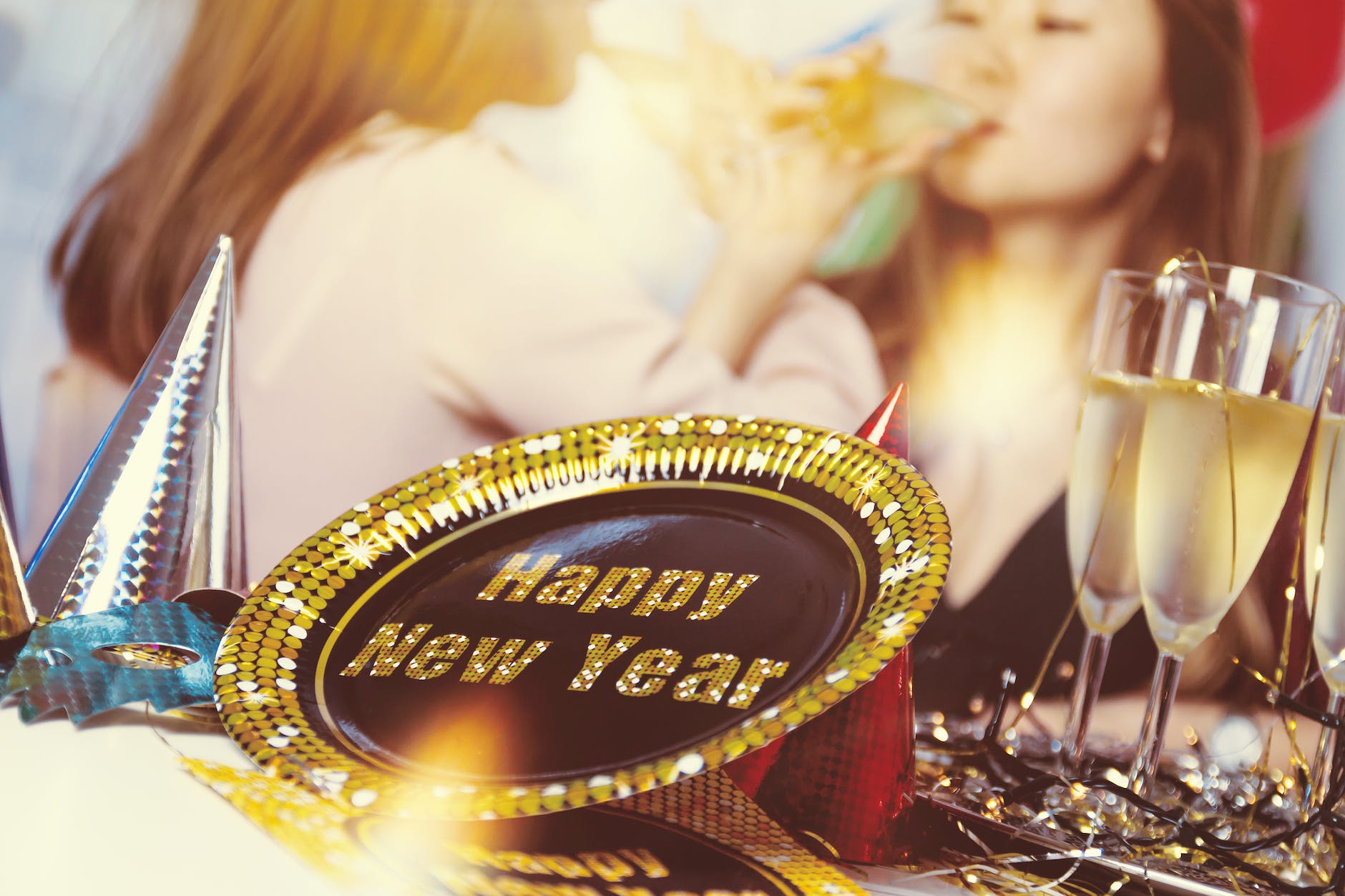 new year party supplies on table with women drinking champagne